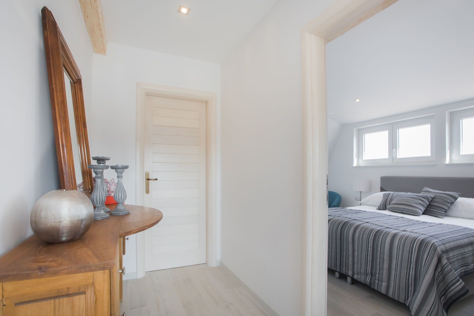 A bedroom with a bed, a bedside table, and a mirror.