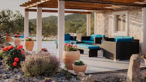 Ein Außenbereich mit Sitzgelegenheit, einer Pergola, Steinmauern und Blumentöpfen.