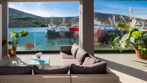 A modern living room with a large window overlooking a marina and a lake. - Beachfront Villa Seashell with Pool (Marina)