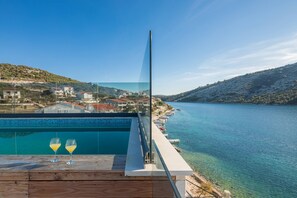 Ein moderner Poolbereich mit freiem Blick auf einen See und die umliegenden Hügel.