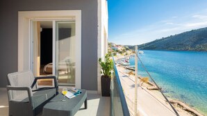 A balcony with wicker furniture, a potted plant, and a view of a coastal area with boats and a clear sky. - Beachfront Villa Seashell with Pool (Marina)