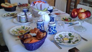 Ein Frühstückstisch reichhaltig gedeckt mit Brot, Gebäck, Früchten und Beilagen.