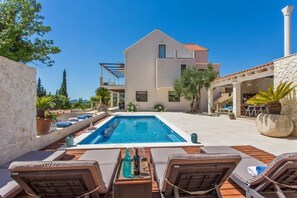 En modern villa med en swimmingpool, en uteplats och en stenmur.