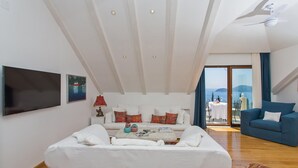Un salon moderne avec un canapé blanc, un fauteuil bleu et un téléviseur à écran plat.