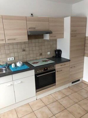 Eine moderne Küche mit hellen Holzschränken, einer schwarzen Arbeitsplatte und einer gefliesten Spritzschutzwand.