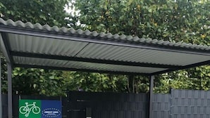 Un espace de stationnement pour vélos abrité, avec un panneau indiquant qu’il fait partie du réseau « E-Bike Ladestation ».