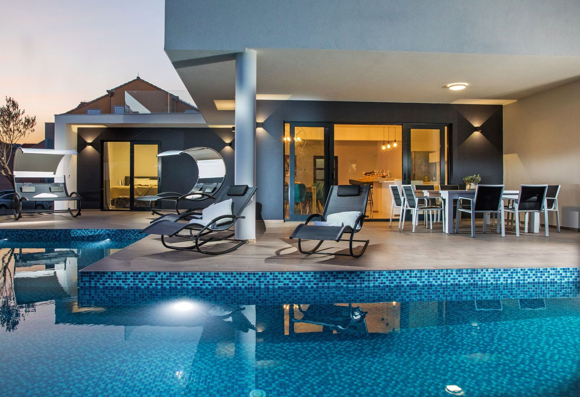 Ein moderner Poolbereich im Freien mit Liegestühlen und einer Essgelegenheit.