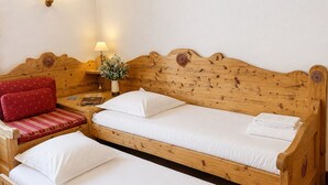 A wooden bed with two pillows and a red upholstered bench with a cushion. - Cozy apartment in Chamonix center with parking (Chamonix-Mont-Blanc)