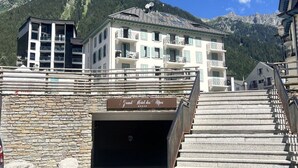 A hotel entrance with a stone wall, a sign reading 'Grand Hotel das Alpen,' and a staircase leading up to the entrance. - Cozy apartment in Chamonix center with parking (Chamonix-Mont-Blanc)