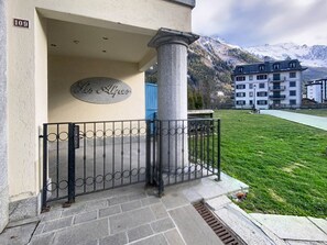 Una entrada de edificio con un pilar de piedra, una verja de metal y un cartel que dice 'Les Alpes'.
