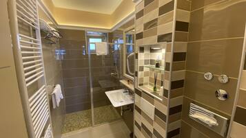 A modern bathroom with a glass-enclosed shower, a white sink, and a vanity with a mirror.