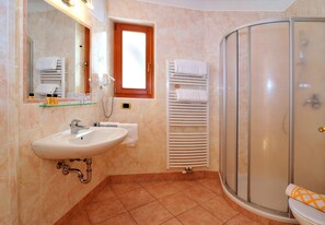 A bathroom with a sink, mirror, towel rack, and shower. - Hotel Hochrain (Naz Sciaves)