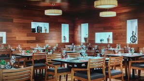 Un restaurant aux murs en bois, doté de nombreuses tables et chaises, et dont les luminaires sont suspendus au plafond.
