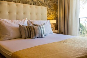 A bed with a tufted headboard, multiple pillows, and a bedside lamp. - Integrated Hotel Arbia - Margita Deluxe (Rab)