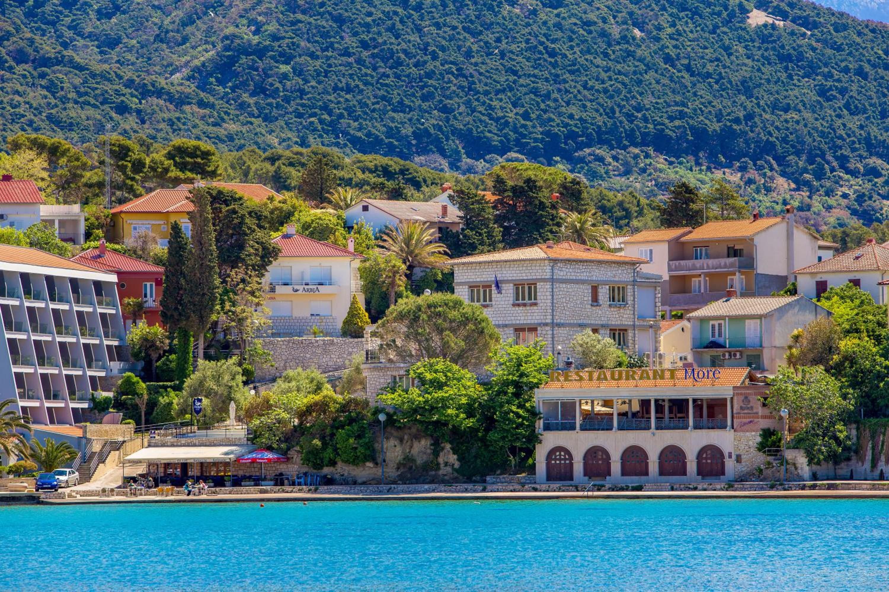 A coastal town with a variety of buildings, including a hotel with a pool and a restaurant.