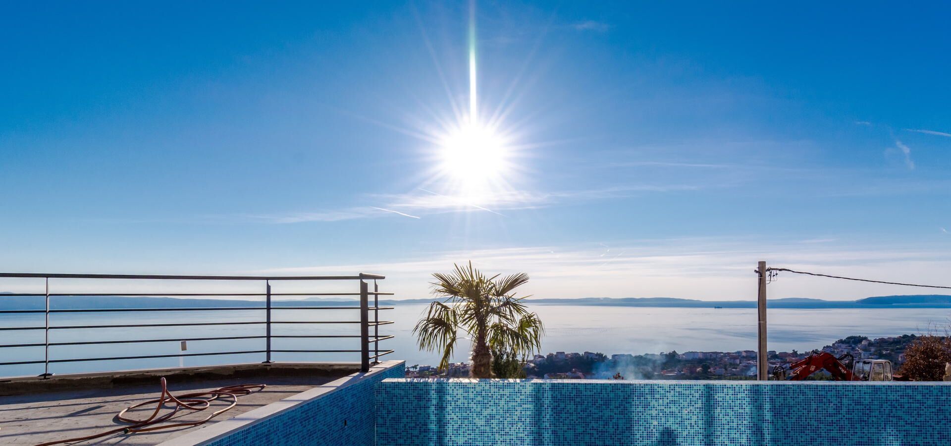 A rooftop pool with a clear view of the sea and distant mountains.