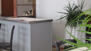 A reception desk with a white counter, a chair, a potted plant, and a wall with a handwritten message.