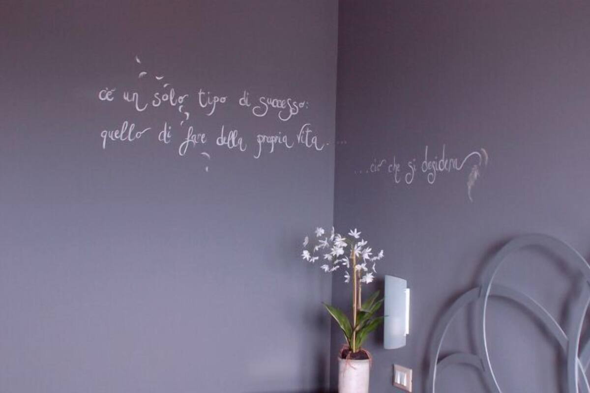 A wall with a potted plant and a wall-mounted light fixture.