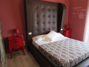 A bedroom with a large bed, a red nightstand, and a red dresser.