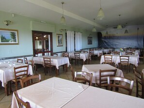 A dining area with multiple tables and chairs, arranged in rows.