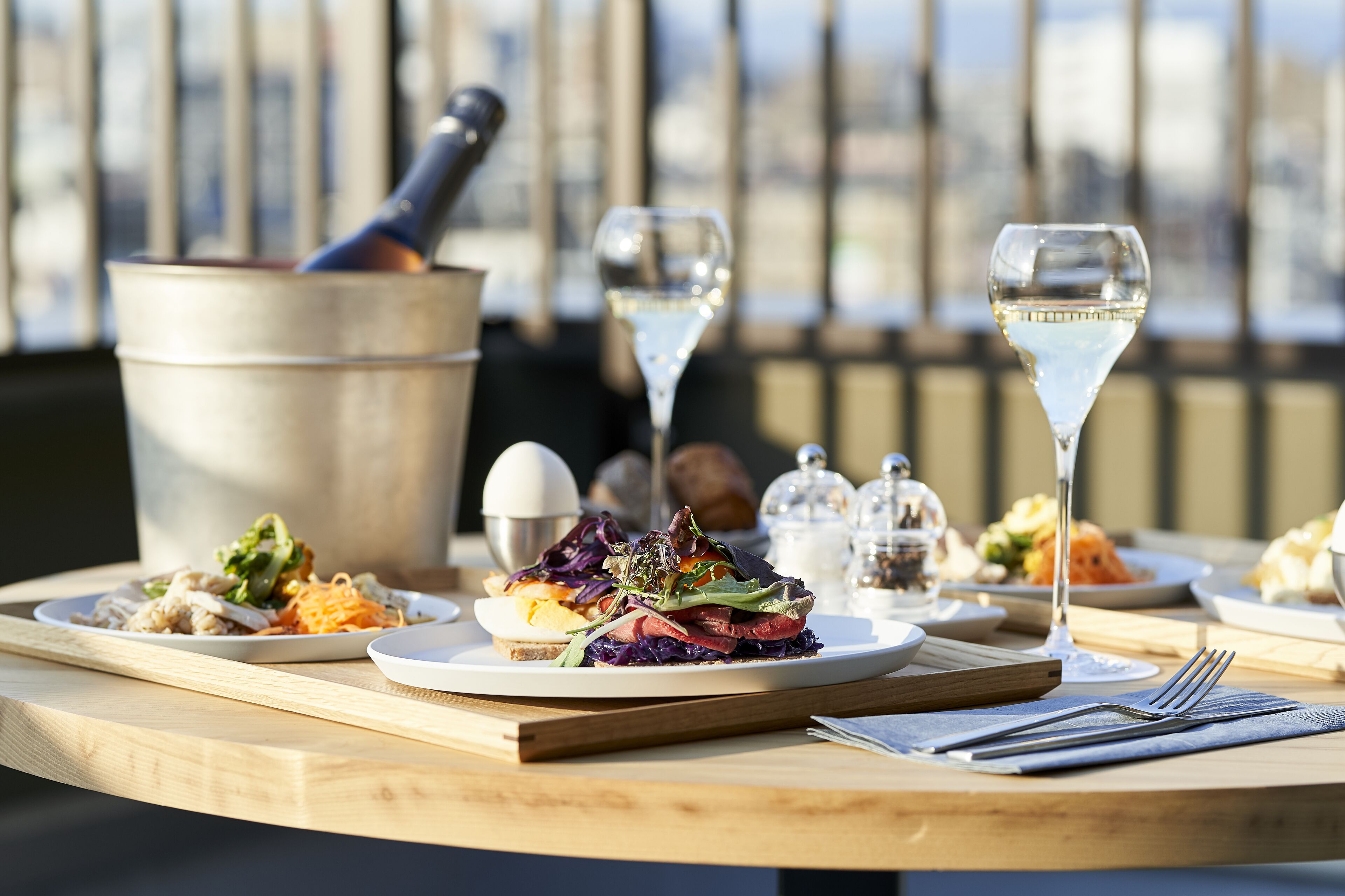 A dining table with plates of food, wine glasses, and cutlery.