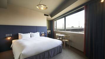 Ein Hotelzimmer mit einem großen Bett, einem kleinen Tisch und einem Fenster mit Blick auf die Stadt.