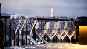 A row of empty wine glasses on a balcony with a cityscape and a tower in the background.