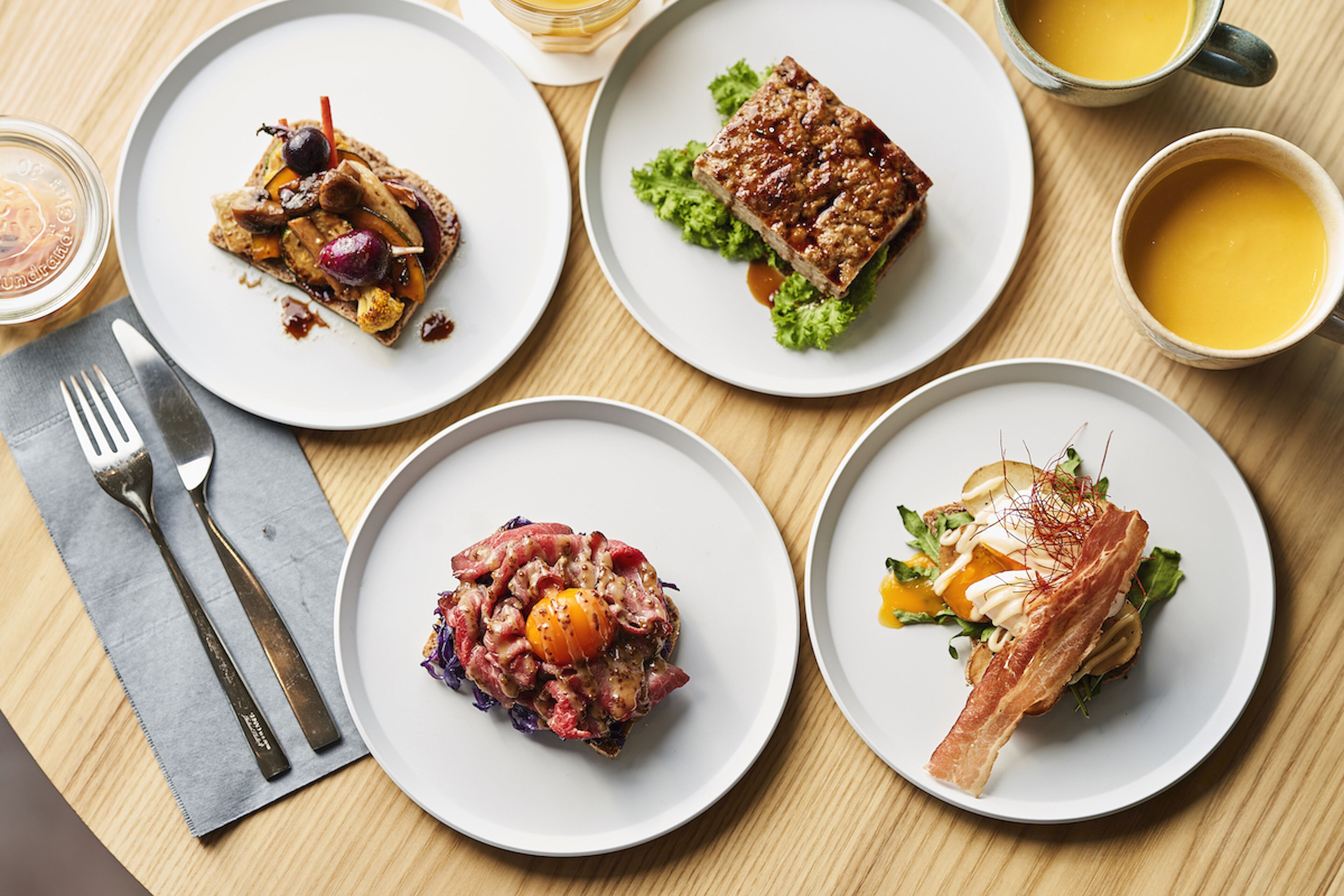 Four plates of food on a wooden table.