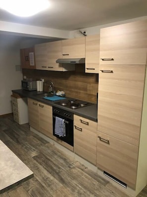 Une cuisine de taille réduite, dotée de meubles en bois, d’un four à micro-ondes, d’un évier et d’une cuisinière.