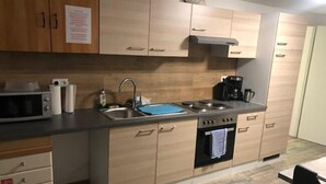 Una cocina moderna con armarios de madera, un lavamanos de acero inoxidable, un microondas, una estufa y una cafetera.