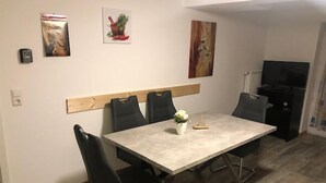 Un comedor con una mesa rectangular, sillas negras y un pequeño jarrón con flores.