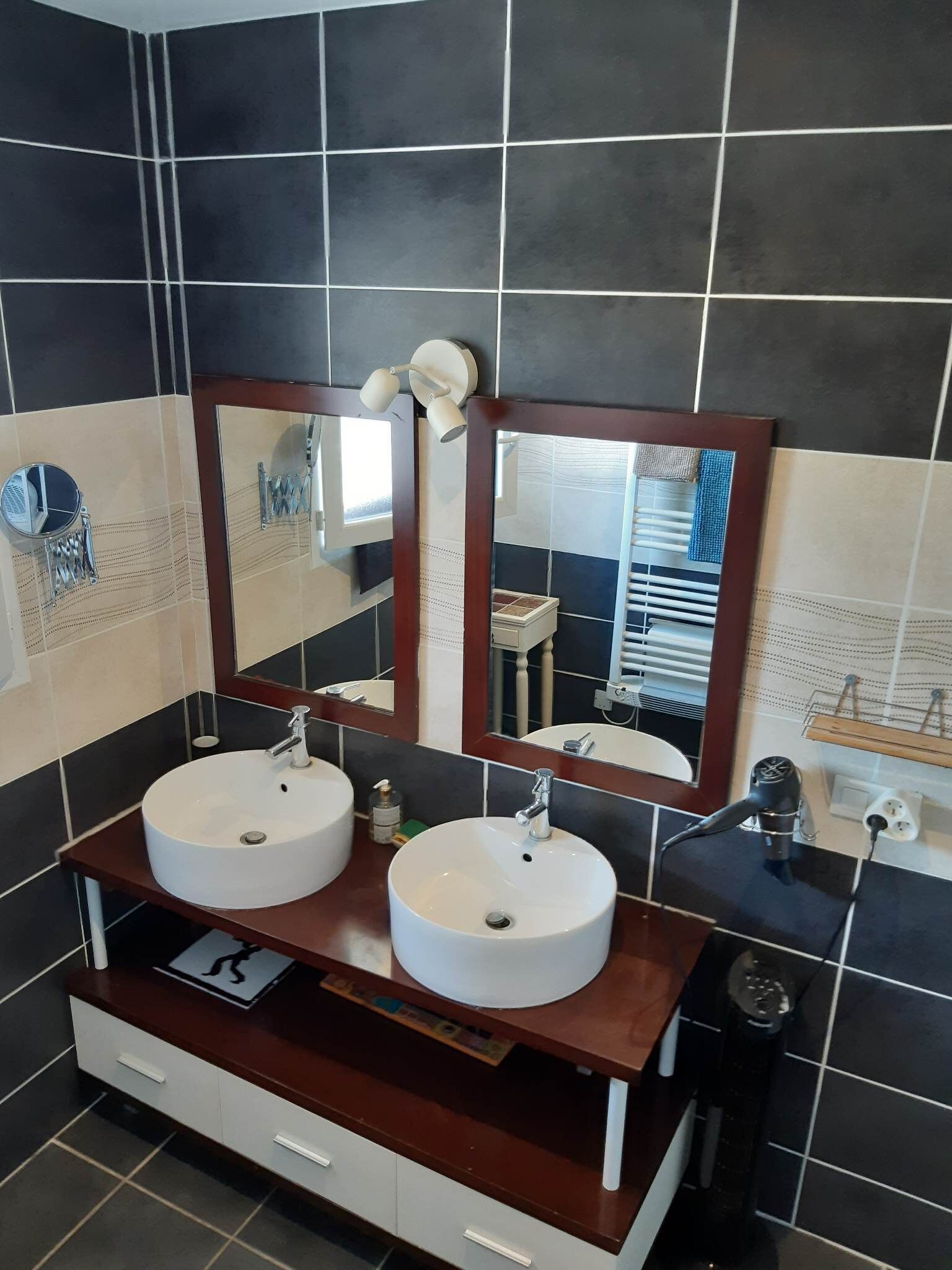 Une salle de bain avec deux lavabos, un miroir et un meuble-lavabo avec des tiroirs.