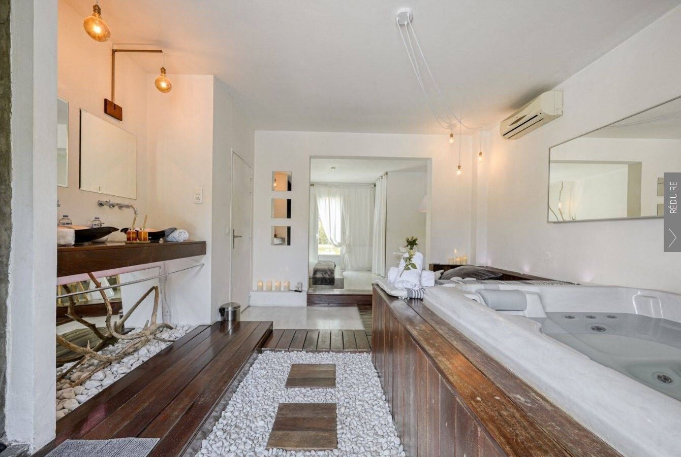 A modern bathroom with a wooden vanity, a large bathtub, and a separate shower area.