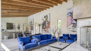 A modern interior with blue sofas, a glass coffee table, and abstract art on the walls. - Mas Sainte Marie - Private Hot Tub Suites (Saint-Laurent-d'Aigouze)
