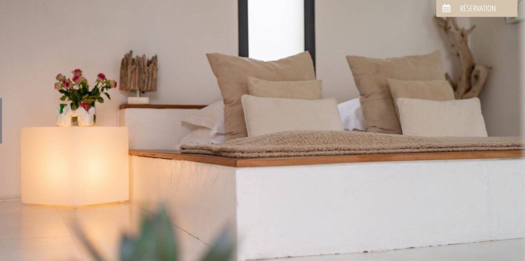 Ein modernes Schlafzimmer mit einem Bett, Kissen, einem Nachttisch und einer Blumenvase.