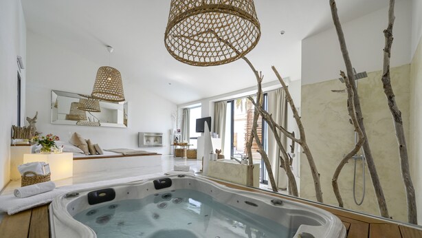 A modern spa room with a hot tub, wicker lamps, a large mirror, and a view of the outdoors. - Mas Sainte Marie - Private Hot Tub Suites (Saint-Laurent-d'Aigouze)