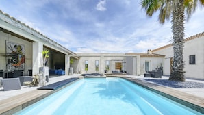 A swimming pool with a wooden deck, lounge chairs, and a palm tree. - Mas Sainte Marie - Private Hot Tub Suites (Saint-Laurent-d'Aigouze)