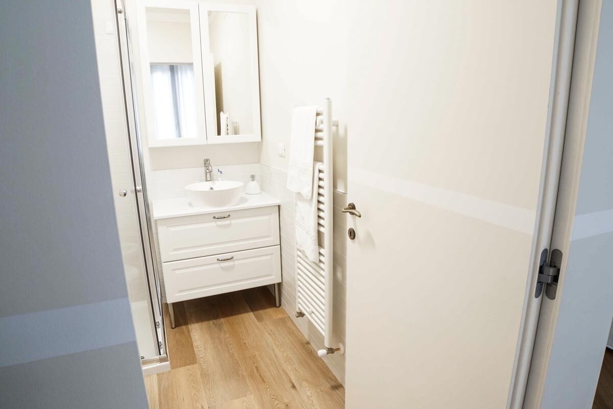 A small, clean bathroom with a white sink, mirror, and towel rack.