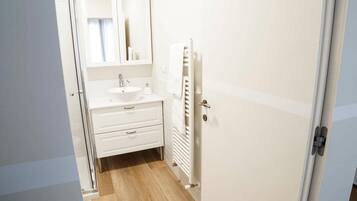 A small, clean bathroom with a white sink, mirror, and towel rack.