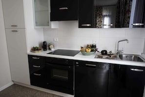 Una cocina moderna con armarios negros, encimera blanca y horno empotrado.
