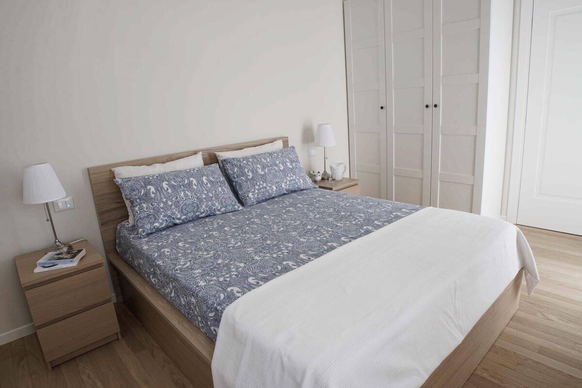 A bedroom with a bed, nightstands, a wardrobe, and a door.