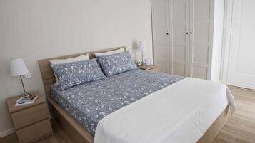 Un dormitorio con cama, mesitas de noche, un armario y una puerta.