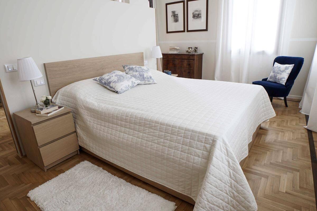 A neatly arranged bedroom with a large bed, bedside tables, a dresser, and a chair.