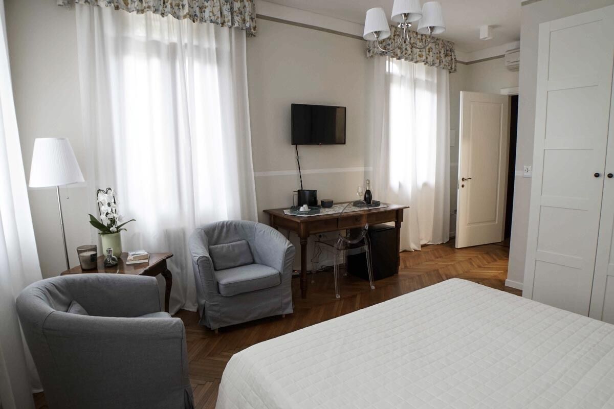 A hotel room with a bed, a desk, a chair, a television, and a door.