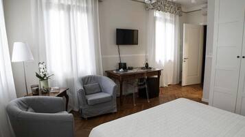 A hotel room with a bed, a desk, a chair, a television, and a door.