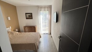 A bedroom with a bed, a dresser, a painting, and a window with curtains.