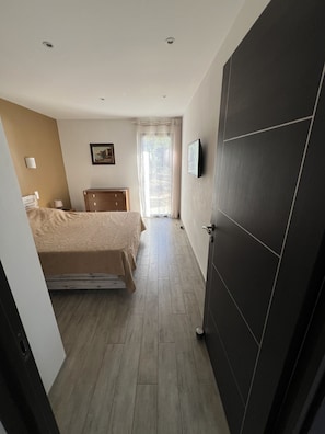 Ein Schlafzimmer mit Bett, Kommode, einem Gemälde und einem Fenster mit Vorhängen.