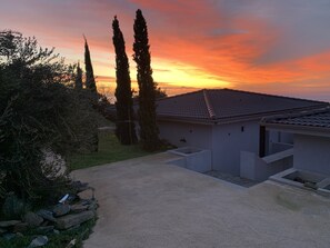 Un edificio residencial con techo de tejas, entrada empaveda y muro de piedra.