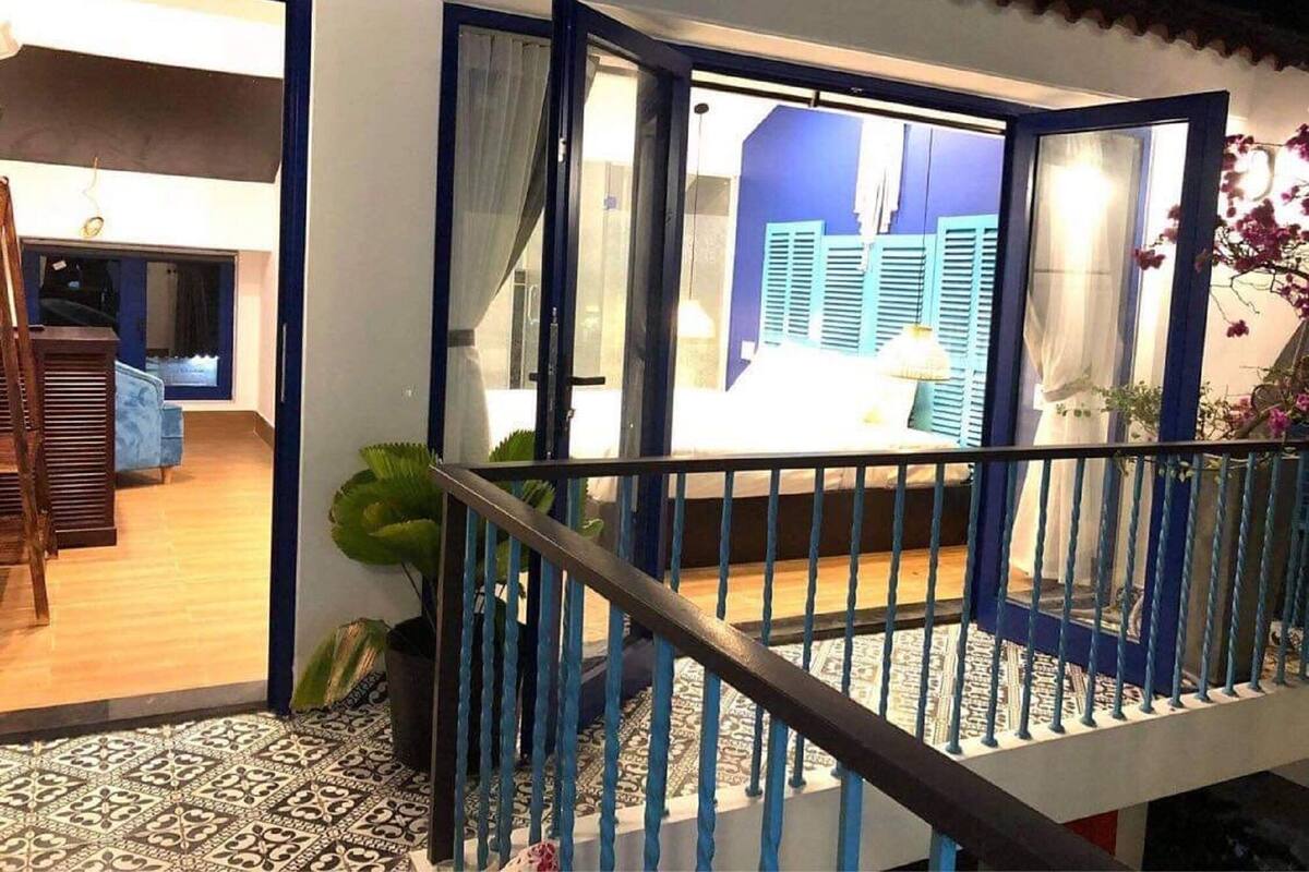 A staircase with blue railings leading to a room with blue shutters and a view of another room.