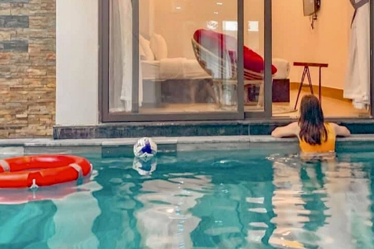A person in a swimming pool with a red lifebuoy and a blue object floating.